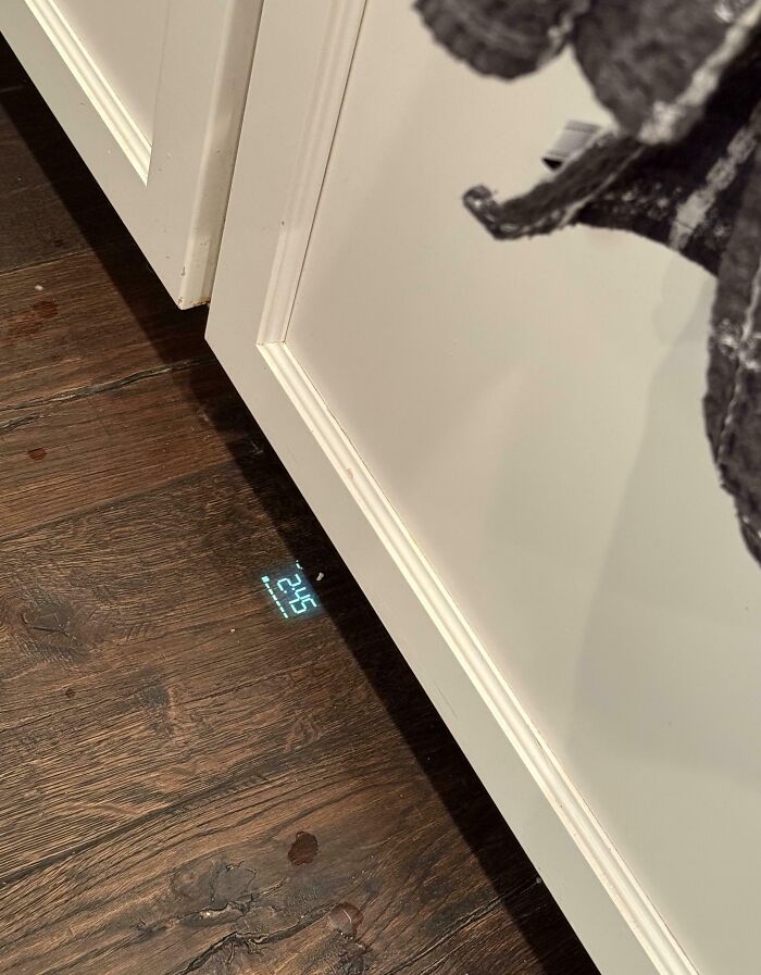 Proyección digital de reloj en suelo de madera junto a mueble blanco como solución genial a problemas habituales.